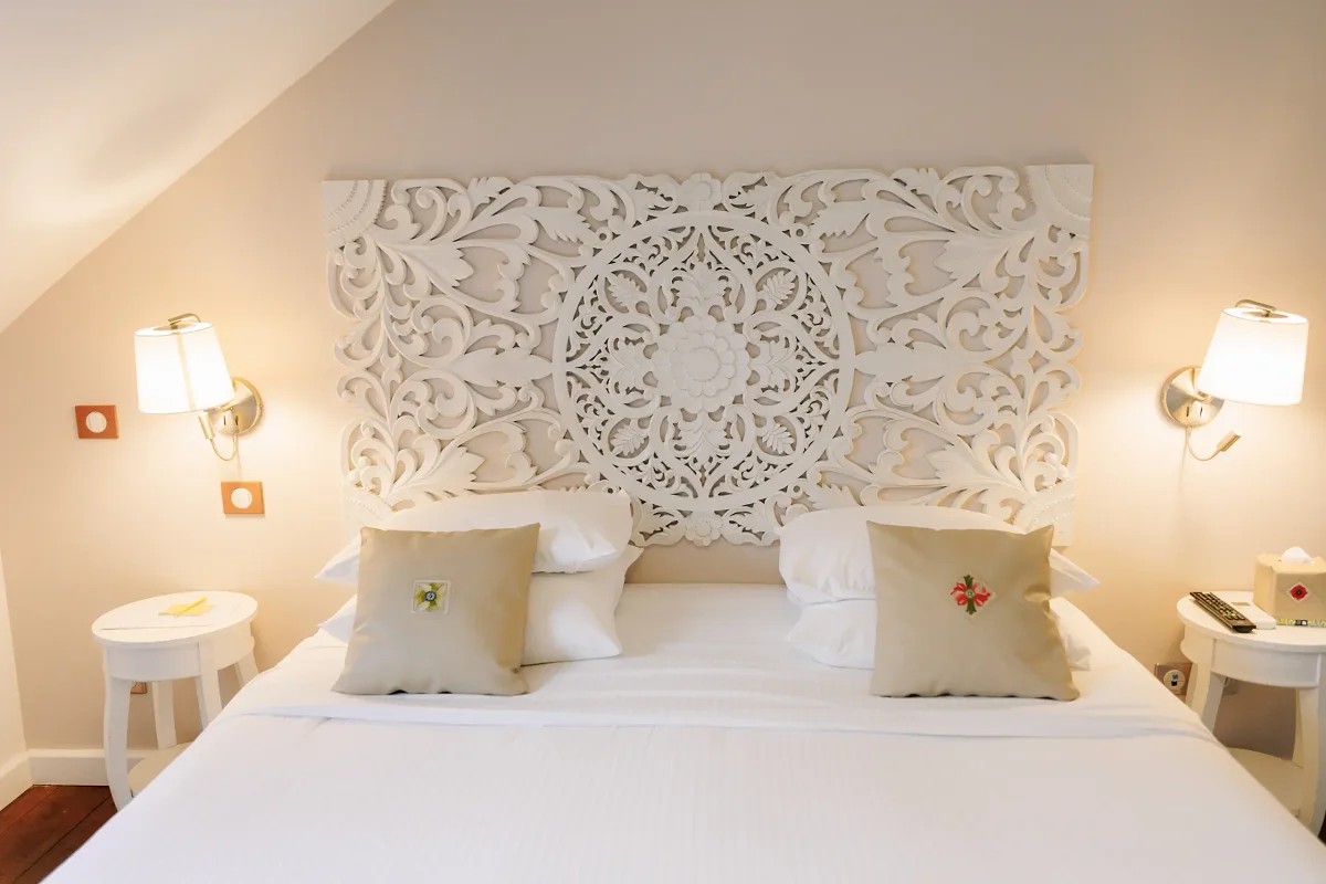 Une chambre du Tsilaosa, son lit king size et sa tête de lit en bois sculpté blanc