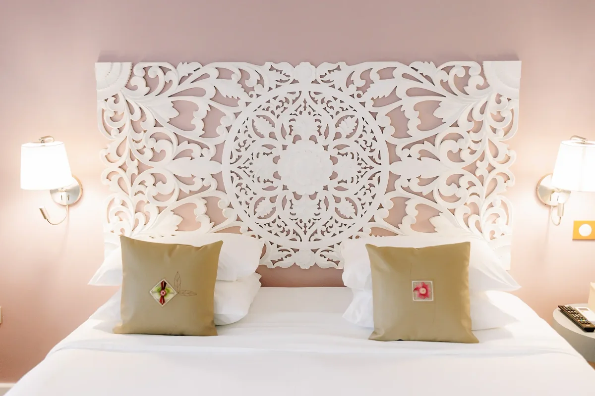 Une chambre du Tsilaosa, sa tête de lit en bois sculpté blanc et ses lampes dorées