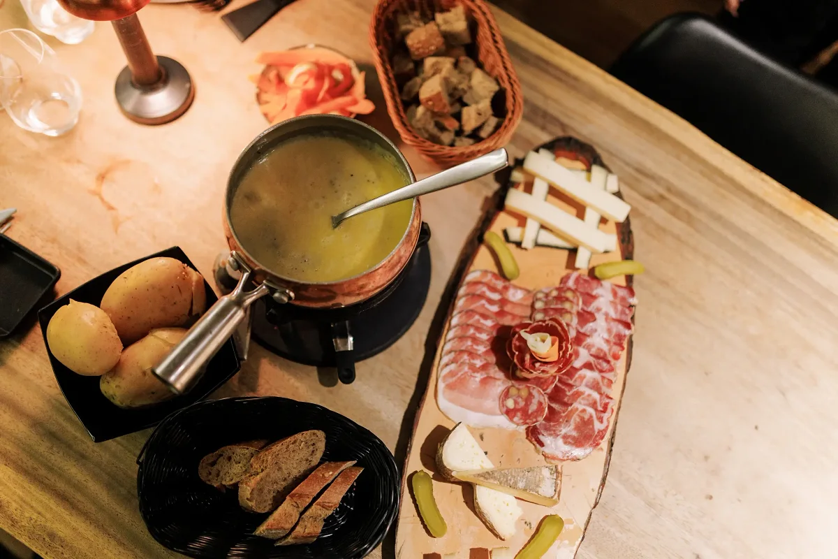 Une fondue, des pommes de terre et une planche de charcuteries vues d'en haut